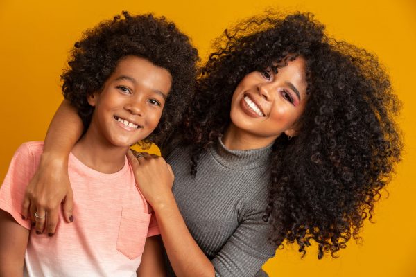 Portrait of young African American mother with toddler son. Yellow background. Brazilian family.