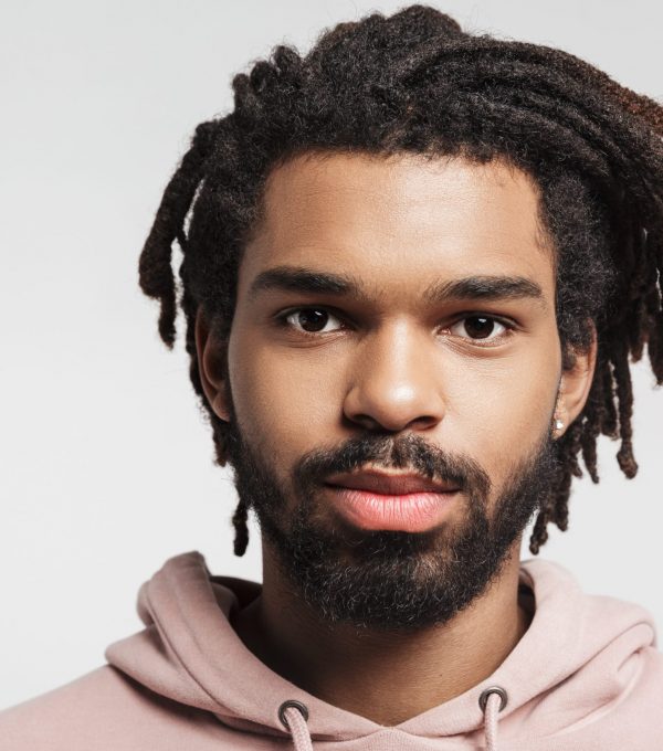 Close up portrait of a young african man wearing hoodie standing isolated over white background, looking at camera